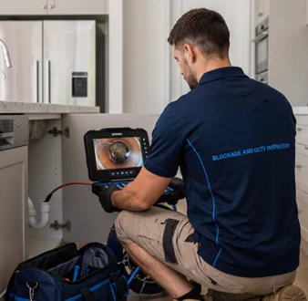 Plumber clearing a blocked toilet in a Hinchinbrook bathroom
